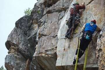 Two rock climbers work on the route entrenched on a rocky ledge. Climbing gear and equipment...