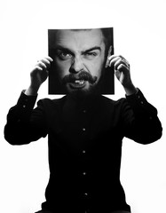 Black and white photo of man in the black shirt holding a photo with the face of a man with a beard in place of his face. Multiexposure