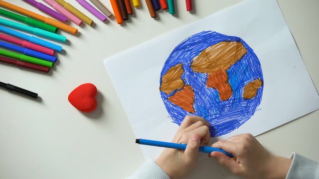 Child painting Earth and putting heart sign, peace all over world, concept