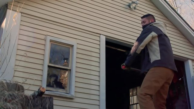 Wood goes flying past camera from strong axe swing & strike from young man