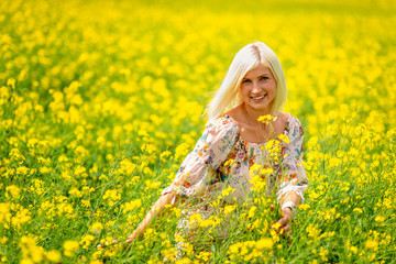 Naklejka na ściany i meble Soft, selective focus. Beautiful, attractive, blond woman in a yellow flower meadow.