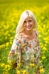 Naklejka na ściany i meble Soft, selective focus. Beautiful, attractive, blond woman in a yellow flower meadow.