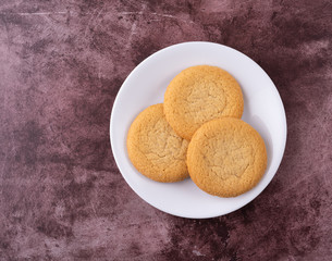 Top view of three soft sugar cookies on a white plate atop a red background