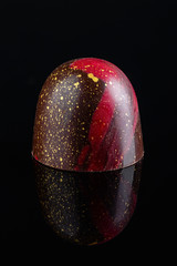 Luxury handmade bonbon decorated with gold and red paint on black background