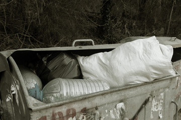 Full garbage cans with garbage. Construction white trash bags filled the container for household waste. The problem of recycling domestic waste