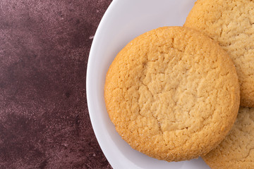 Top close view of three soft sugar cookies on a white plate atop a red background