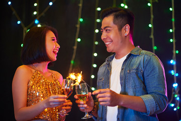 Happy Vietnamese couple with champagne glasses and sparklers enjoying party