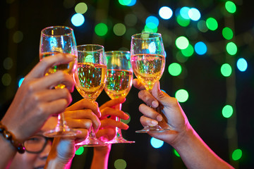 Group of people cheering with sparkling wine glasses at party