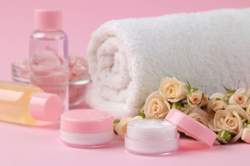 Obraz na płótnie Canvas cosmetics for face and body in pink bottles with fresh roses on a delicate pink background. cream and lotion. spa.