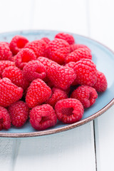 Fresh raspberries in a plate on a  vintage background.