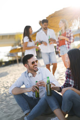 Obraz premium Happy couple smiling and drinking beer at beach