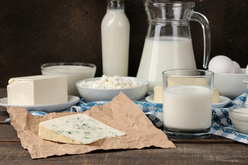 milk products. milk, sour cream, cheese, butter and cottage cheese on a brown wooden table