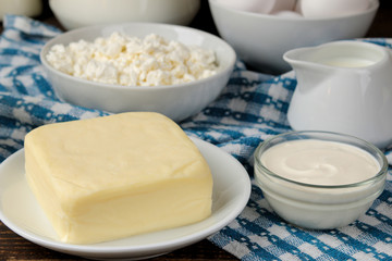 milk products. milk, sour cream, cheese, butter and cottage cheese on a brown wooden table