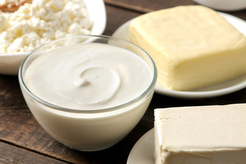 milk products. milk, sour cream, cheese, butter and cottage cheese on a brown wooden table