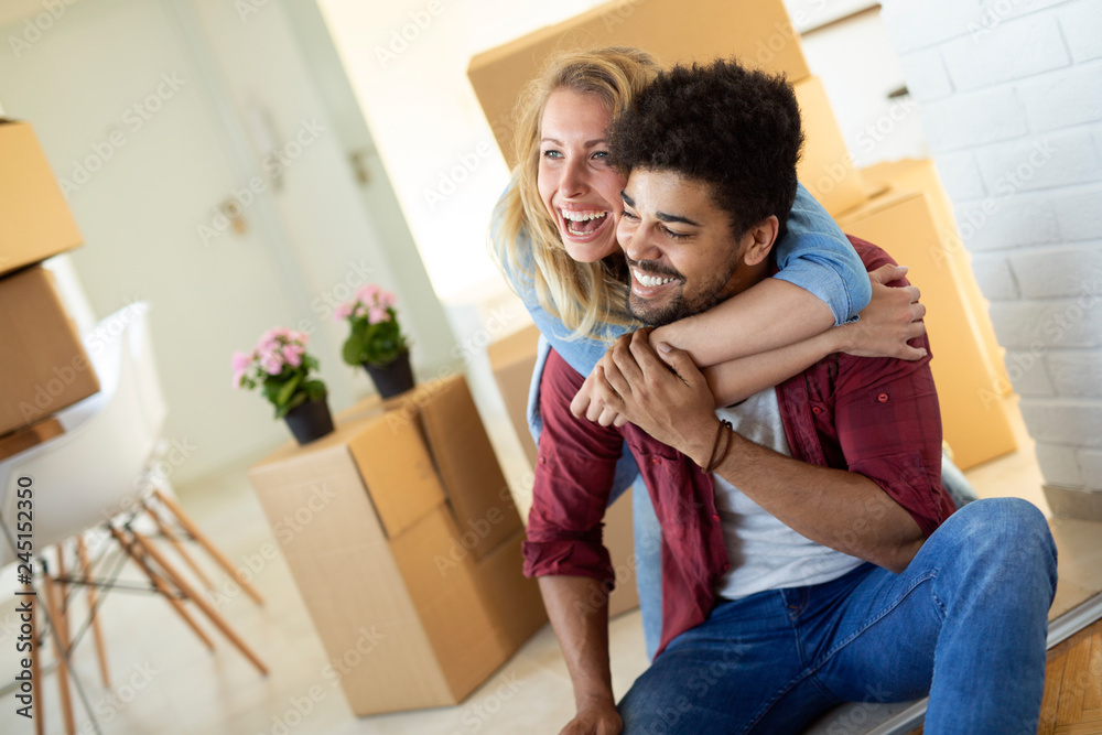 Wall mural Young couple unpacking cardboard boxes at new home moving in concept