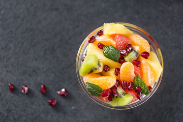 Bowl of healthy fresh fruit salad on black background.