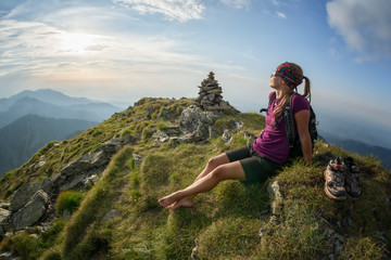 Naklejka na ściany i meble Young girl relaxing on the peak in the sunset and enjoying the view