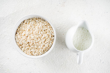 Healthy cereal and milk breakfast concept, dry oats in small bowl, with milk and fresh blueberry, white  wooden concrete background copy space