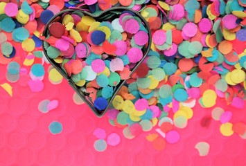 festive carnaval concept with colorful confetti and heart shape. Party background and text space