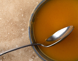 Bowl of butternut squash soup with a spoon on a marble table