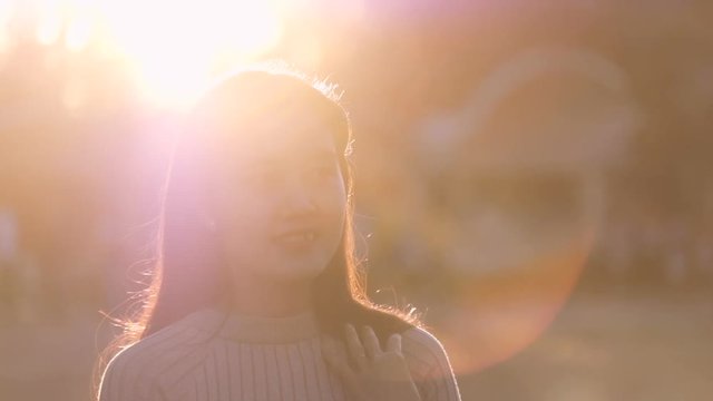 Beautiful Asian girl smile in the sunshine. Royalty high-quality stock video footage of a pretty Asia young woman with long hair nice smiling in sun light backlit. Beautiful girl in sunlight backlight