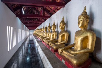 Row of golden buddha statues in the terrace of Wat Phra Sri Rattana Mahathat , Wat Yai or Wat Buddha Chinnarat temple.