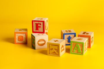 Colorful wooden blocks with letters on a yellow color background