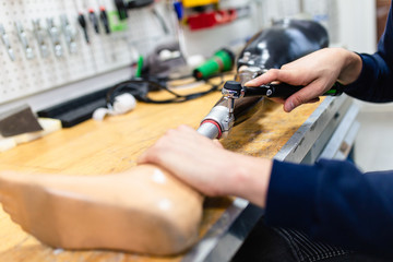 Disabled man working in amputee shop for production prosthetic extremity parts.