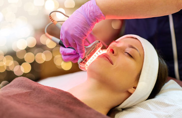 Obraz na płótnie Canvas people, beauty, cosmetic treatment, cosmetology and technology concept - beautician with microdermabrasion device doing face exfoliation to young woman lying at spa