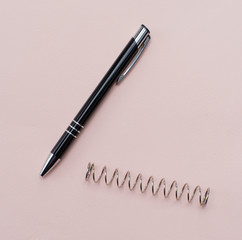 Fototapeta premium black ballpoint pen on a paper background. metal spring on the background