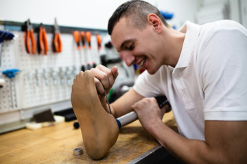 Disabled man working in amputee shop for production prosthetic extremity parts.