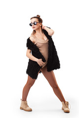 Young brunette woman in black vest and tights posing on grey background