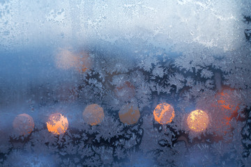 Christmas frosty snowflake pattern on the window glass and city lights