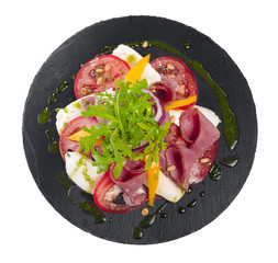 Fresh italian caprese salad with mozzarella and tomatoes on dark plate