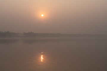 Fototapeta na wymiar The setting sun in the fog at Sundarbans in West Bengal in India