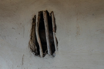 A window with a lattice of twigs in a clay wall in India