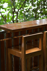 Fototapeta na wymiar Close up wooden table and chair on terrace and green tree background