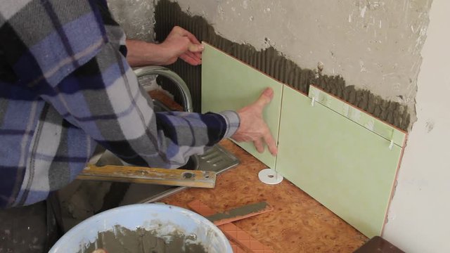 Master glues the tile on the wall.