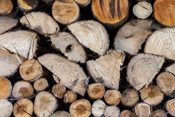 Background of dry chopped firewood logs stacked up on top of each other in a pile.