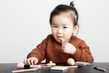 Naklejka premium Beautiful cute Asian little girl playing makeup game