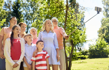 generation and people concept - happy family taking picture with smartphone and selfie stick in summer garden