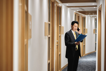 Asian Manager Working As Banking Agent Talking On Cell Phone