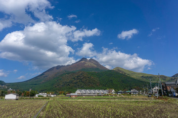 Fototapeta na wymiar Beautiful lanscape panorama of Yufuin village and Yufu mountain in Background with blue sky and clouds in autumn leaves. onsen town, Yufuin, Oita, Kyushu, Japan