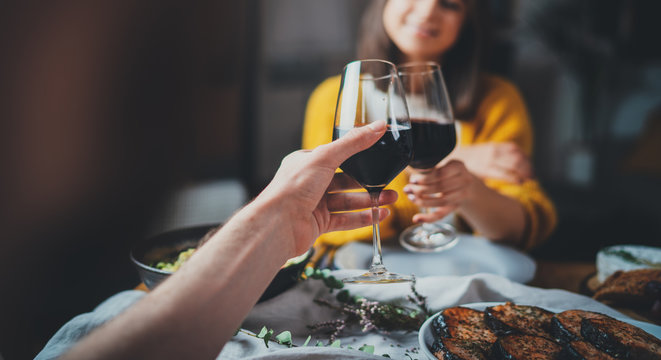 Cropped image of romantic couple making cheers with glasses of red wine during date in restaurant, Love Relationship Celebration Concept