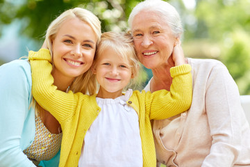 family, generation and people concept - happy smiling woman with daughter and senior mother sitting on park bench