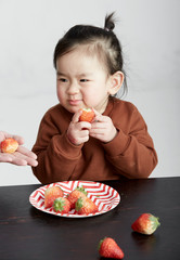 Beautiful cute Asian little girl eating fruits