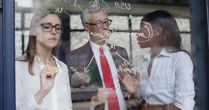 4K Attractive mixed ethnicity business team writing on glass wall & brainstorming