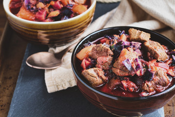 Bowl of Borscht soup with hearty, meaty chunks of beef, root vegetables, cabbage and beets. High angle view.