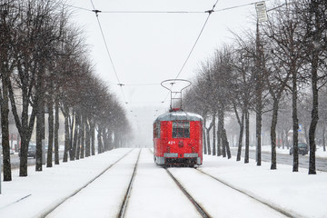 Old red tram on a snowy street.