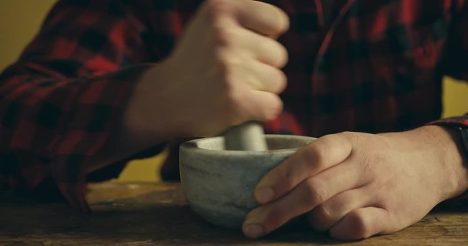 Young man grinding spices with pestle and mortar